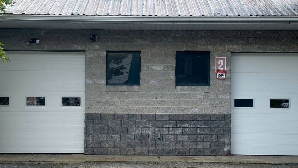 Two white commercial sectional doors on a block service building