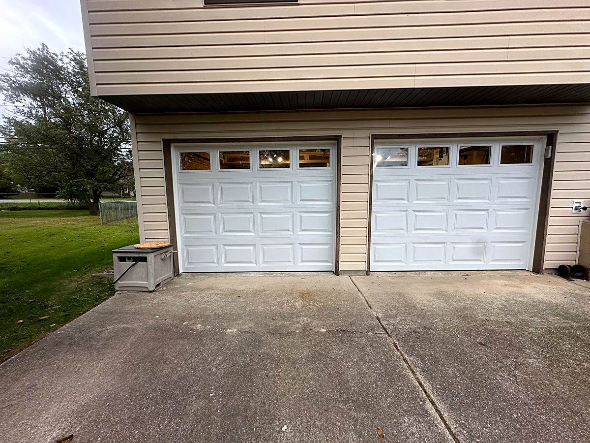 Two white raised panel garage doors with window tops on a home in Hanover
