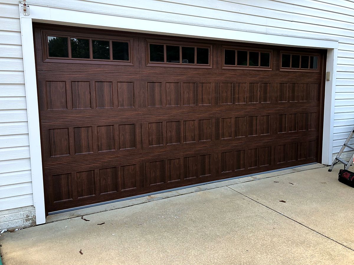 Dark wood look two car garage door with windows in Parkville